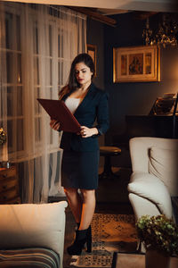 Full length of woman standing on sofa at home