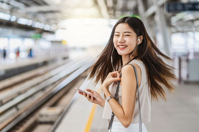 Young woman using mobile phone at railroad station