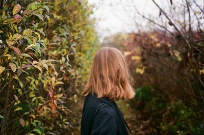 Rear view of woman standing against trees