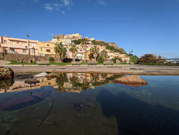 Lake by buildings against blue sky