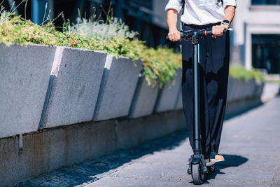 Low section of man on push scooter at roadside