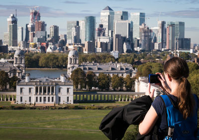 Full length of photographer photographing buildings in city