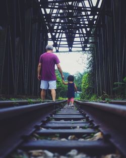 Rear view of people walking on railroad track