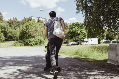 Father walking with male toddler in baby carriage on road during sunny day