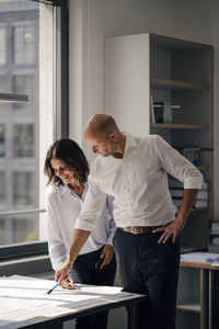 Two architects working in office, discussing blueprints