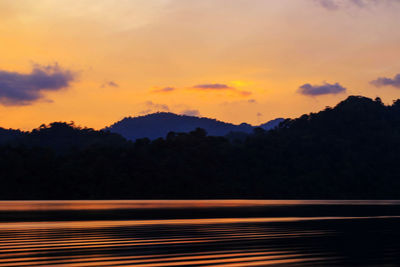 Scenic view of silhouette mountains against orange sky