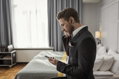 Side view of businessman listening to mobile phone in hotel room