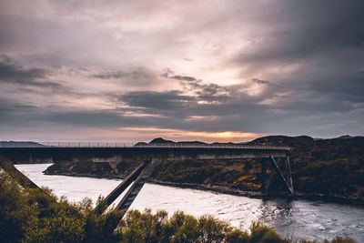 Bridge over river against sky during sunset