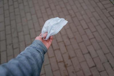 As a safety from the virus,a man's hand holds a medical mask in his hand, in the city, an accessory