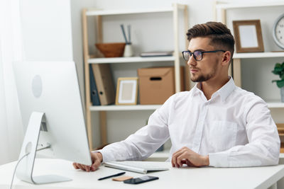 Young man using laptop at desk in office