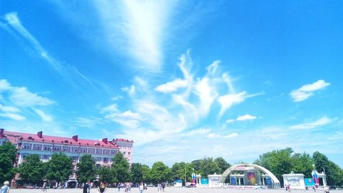 People in front of buildings against cloudy sky