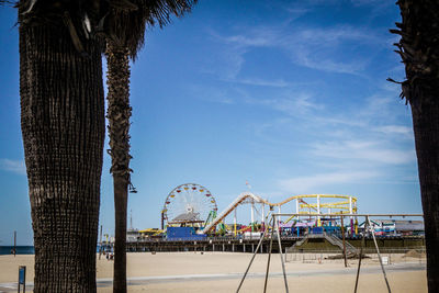 Ferris wheel at beach against sky