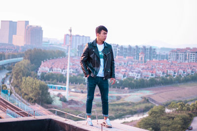 Man standing on building terrace against cityscape