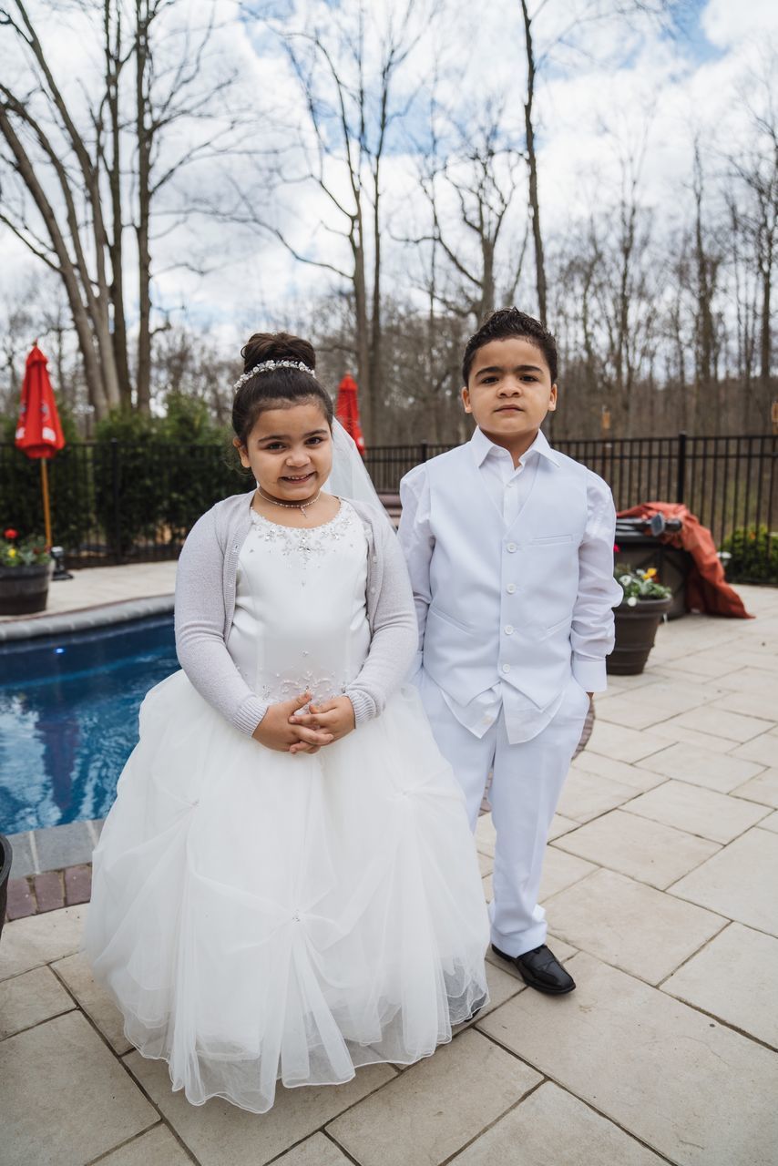 real people, two people, looking at camera, full length, white color, lifestyles, tree, front view, day, portrait, togetherness, smiling, wedding, emotion, plant, clothing, women, nature, adult, outdoors, couple - relationship, positive emotion