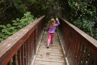 Rear view of woman standing on footbridge