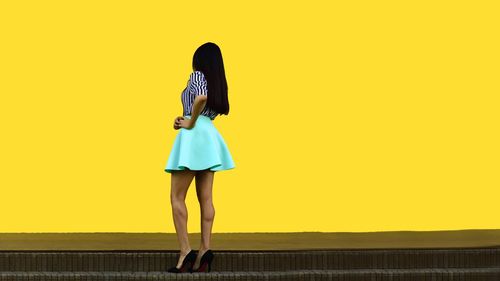Rear view of woman standing on yellow umbrella