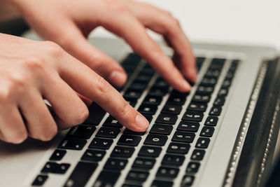 Cropped hand of person typing on laptop