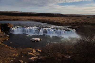 Scenic view of waterfall against sky