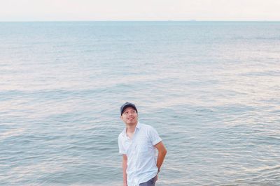 Portrait of smiling woman standing in sea against sky