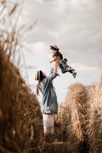 Side view of mother lifting son at farm