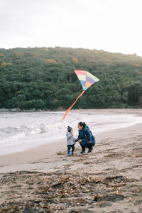Rear view of man with arms outstretched standing at beach