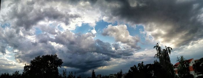 Low angle view of trees against cloudy sky