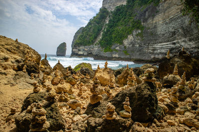Scenic view of rocks by sea against sky