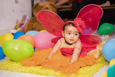 Cute baby girl by colorful balloons during celebration at home