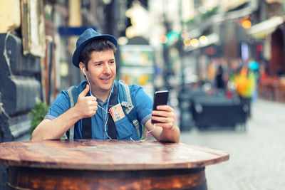 Young man using mobile phone while sitting on table