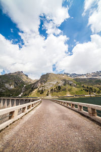 Empty road leading towards mountains against sky