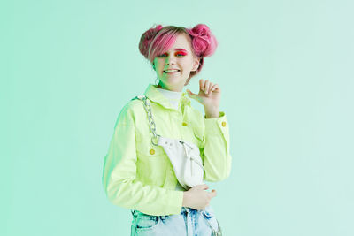 Portrait of young woman standing against blue background