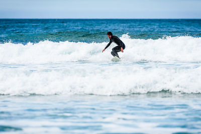 Man surfing in sea against sky