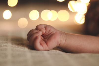 Cropped hand of baby on bed at home