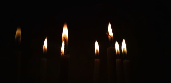 Close-up of lit candles in darkroom