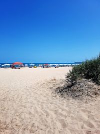 Scenic view of beach against clear blue sky