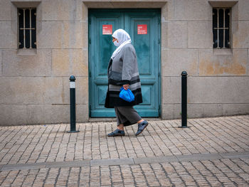 Full length rear view of man walking on street against building