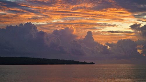 Scenic view of sea against dramatic sky during sunset