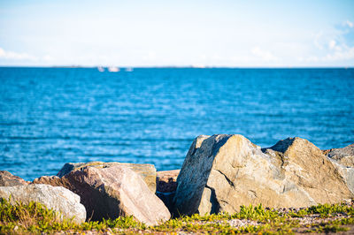 Scenic view of rocks by sea against sky