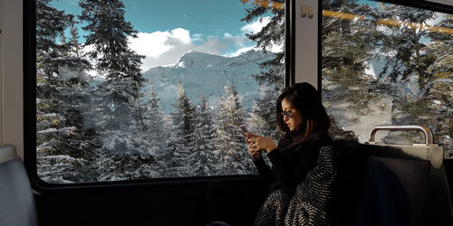 Woman looking through window in winter