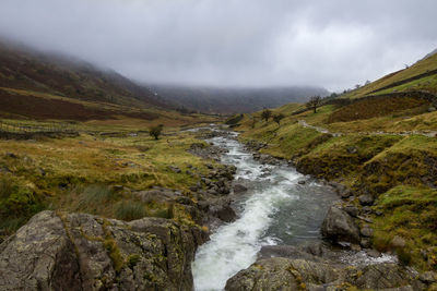 Scenic view of river by mountains against sky
