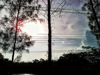 Low angle view of electricity pylon against cloudy sky