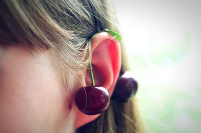 Close-up of woman with cherries on ear