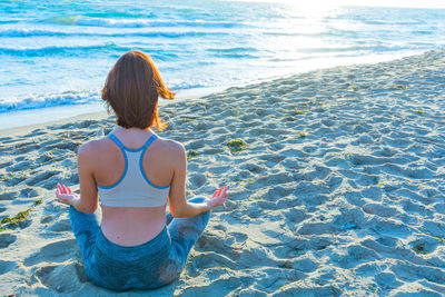 Rear view of woman sitting on beach