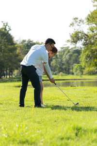 Full length of couple playing golf on field