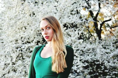Portrait of young woman standing against tree