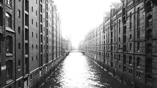 Canal amidst buildings in city against clear sky
