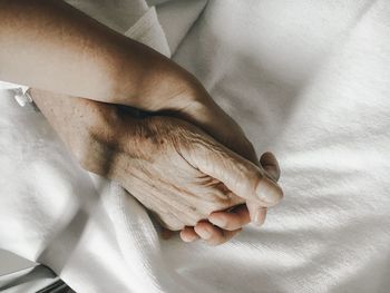 Close-up of people holding hands on bed