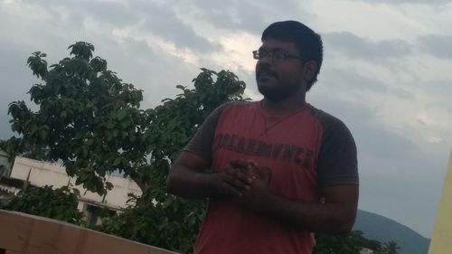 Man standing by tree against sky