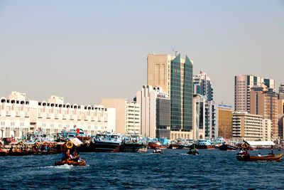 Boats in city by buildings against clear sky