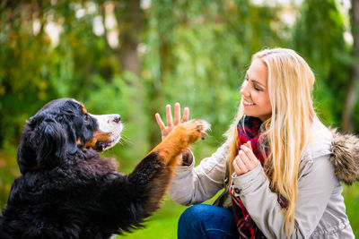 Side view of happy woman playing with dog in park